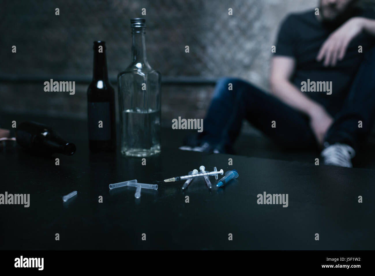 Flaschen voller Alkohol und Spritzen liegen in der Droge-Höhle Stockfoto