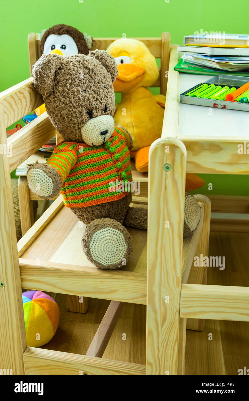 Kinder Zimmer, hölzerne Möbel-Set, Teddybär auf Stuhl, Plüschtiere, Bücher, Buntstifte auf Tisch, Tageslicht, gemütliche Atmosphäre, Nahaufnahme Stockfoto