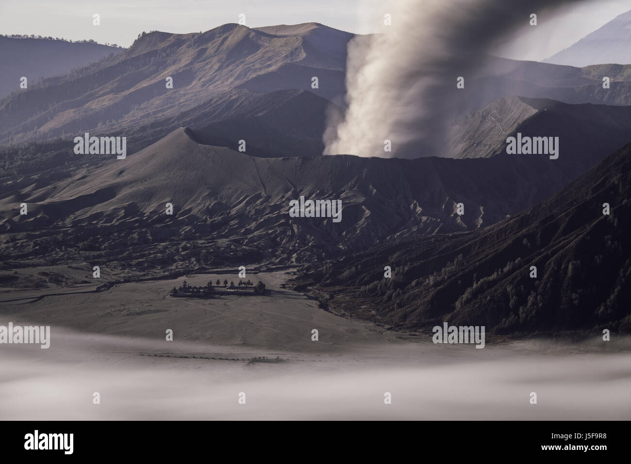 Atemberaubenden Blick auf die flüchtigen und ausbrechenden Gunung Bromo mit Aschewolke aus dem Krater und die ganze Gegend spuckt in dunklen Vulkanasche bedeckt Stockfoto