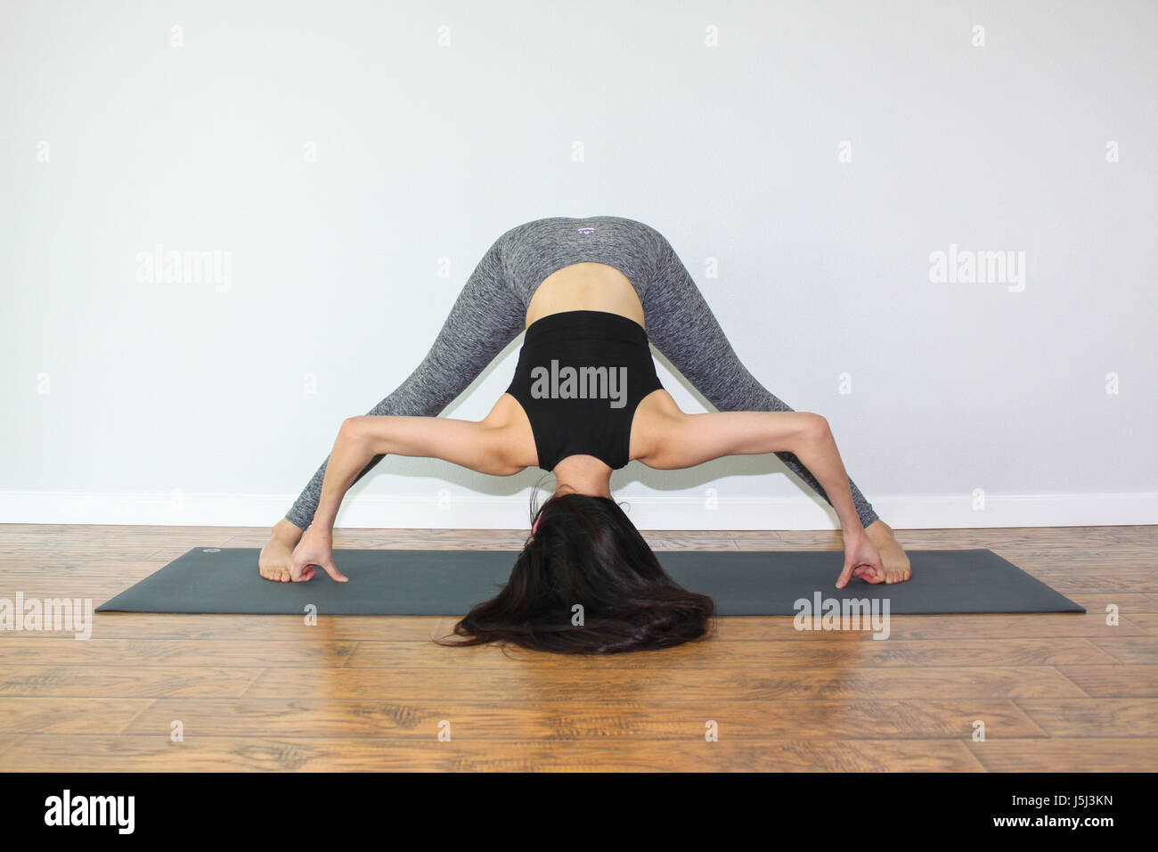 Schöne Frau tut ein Yoga-Pose genannt, breitbeinig stehend nach vorne falten. Stockfoto