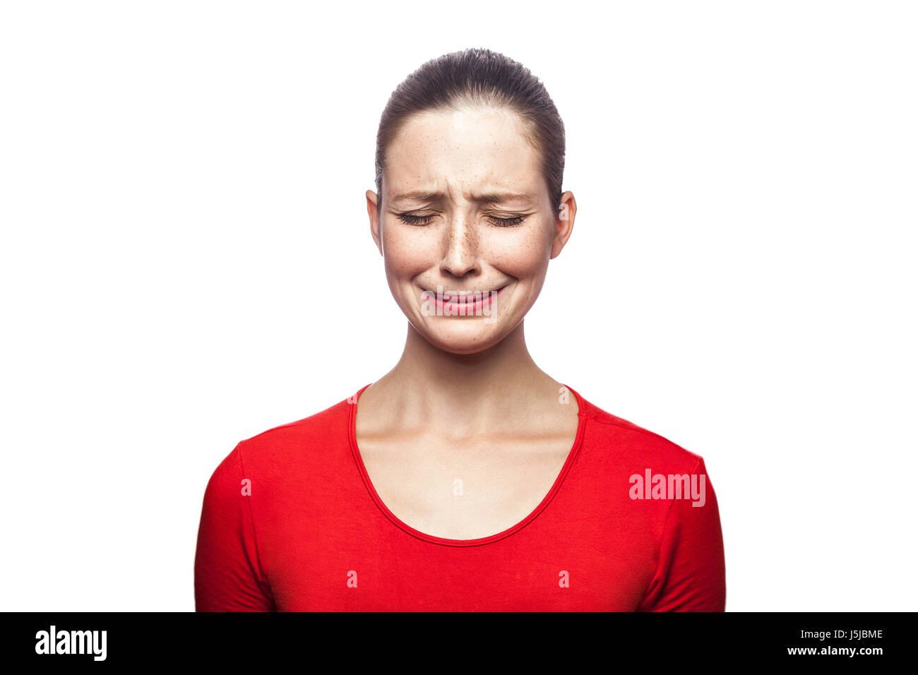 Porträt von traurig unglücklich weinende Frau im roten T-shirt mit Sommersprossen. geschlossenen Augen, Studio gedreht. isoliert auf weißem Hintergrund. Stockfoto