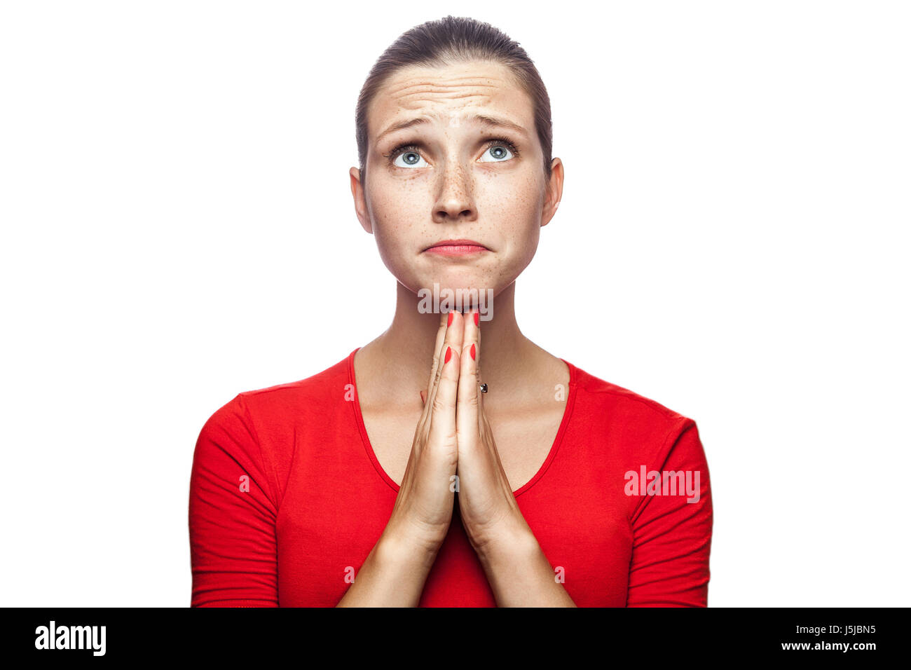 Porträt der unglückliche erfreulich Frau im roten T-shirt mit Sommersprossen. Nachschlagen und wünschte, Studio gedreht. isoliert auf weißem Hintergrund. Stockfoto