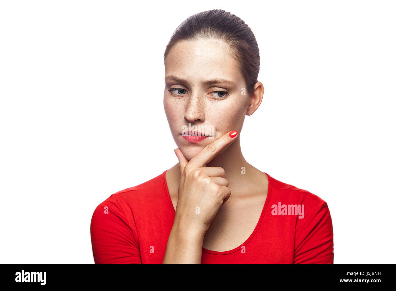 Porträt von nachdenklich ernst Frau im roten T-shirt mit Sommersprossen, Studio gedreht. isoliert auf weißem Hintergrund. Stockfoto