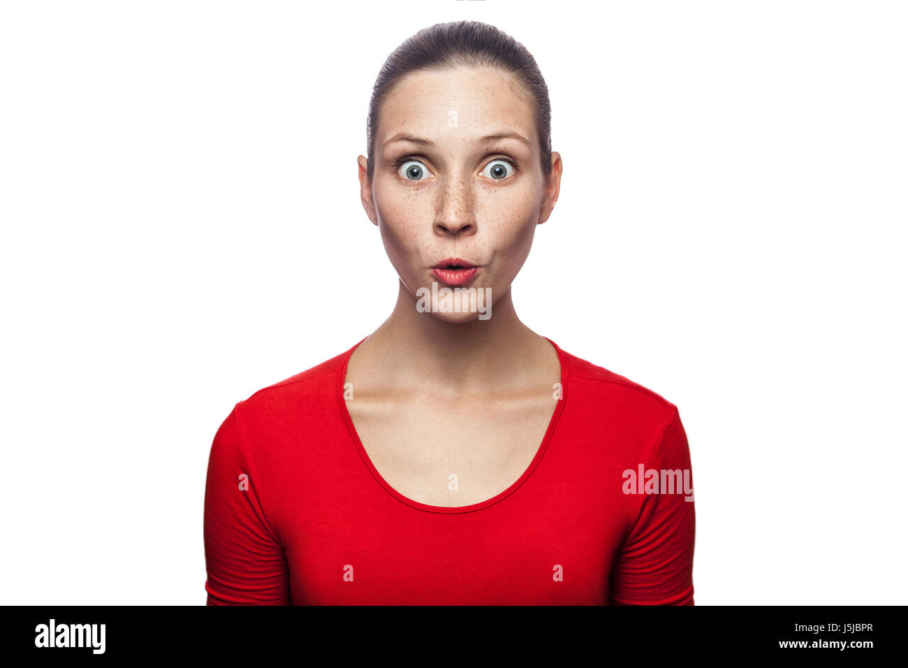 Porträt von glücklich überrascht Frau im roten T-shirt mit Sommersprossen. Blick in die Kamera begeistert mit großen Augen, Studioaufnahme. isoliert auf weißem Hintergrund. Stockfoto