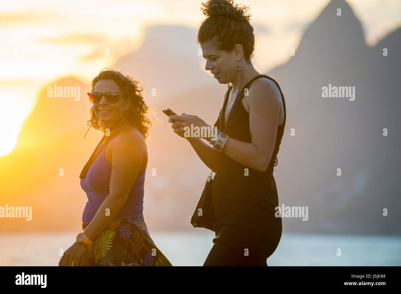 RIO DE JANEIRO - 21. Februar 2017: Junge Frauen Fuß entlang der Promenade am Arpoador, den beliebten Blick auf den Sonnenuntergang von Ipanema zu genießen. Stockfoto