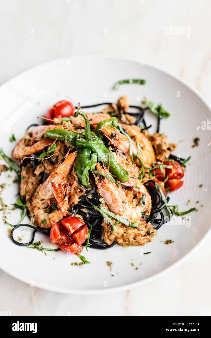 Gourmet-Essen gegrillte Garnelen und Gemüse auf schwarzen Tintenfisch Tinte Nudeln Essen Stockfoto