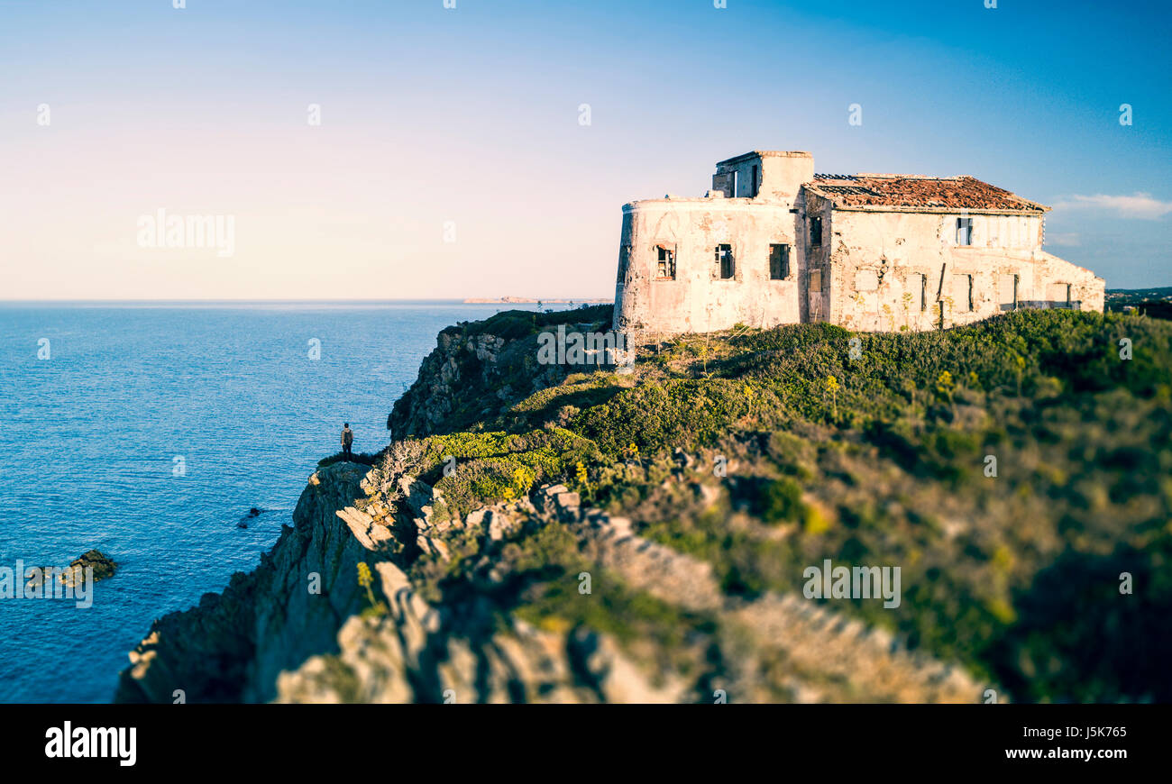 Ein Mann steht auf einer hohen Klippe, genießen den Blick auf eine italienische Küste mit dem Mittelmeer unter ihm. Porto Cervo - Costa Smeralda, Sardinien - Ita Stockfoto