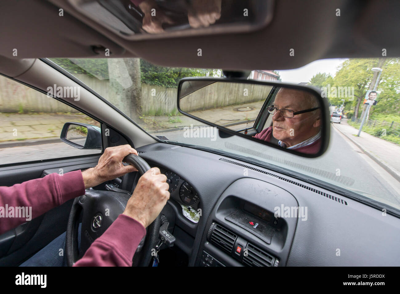 Ältere Gentleman, senior, Rentner, über 75 Jahre alt, fährt mit seinem Auto, Rückspiegel, Stockfoto