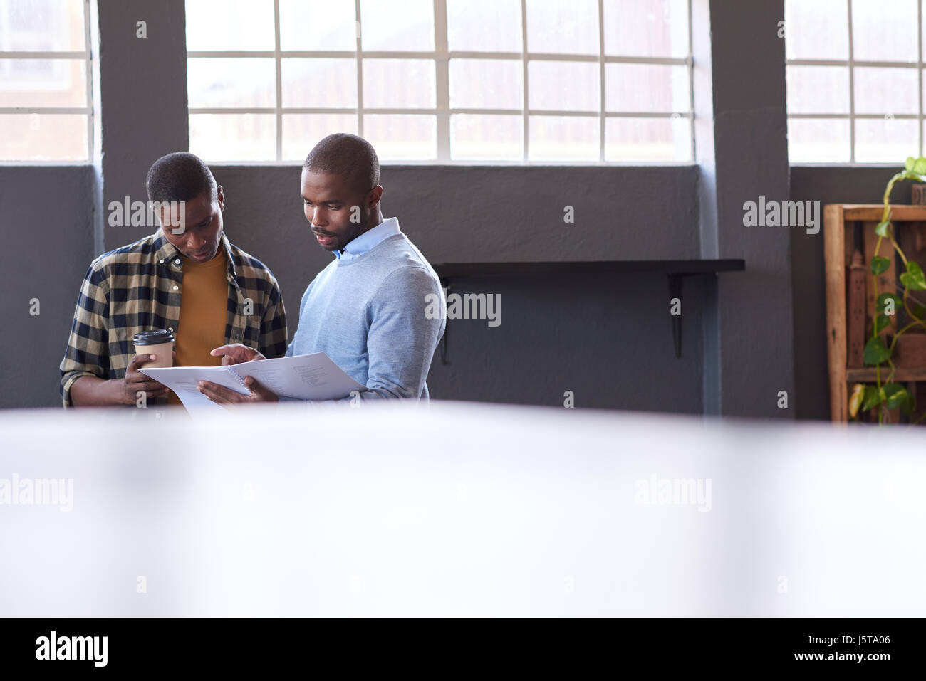 Junge afrikanische Unternehmer diskutieren Papierkram zusammen in einem Büro Stockfoto