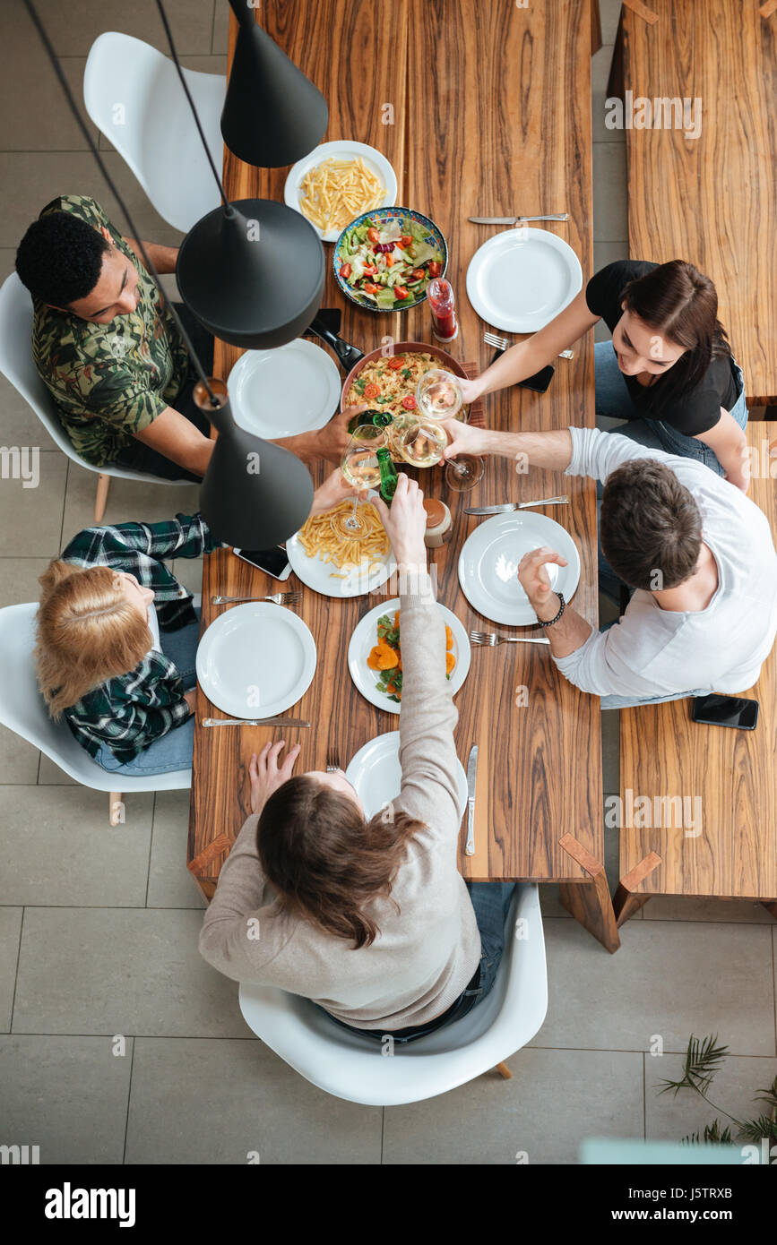 Draufsicht der fünf Menschen jubeln mit Wein beim Sitzen am rustikalen Esstisch Stockfoto