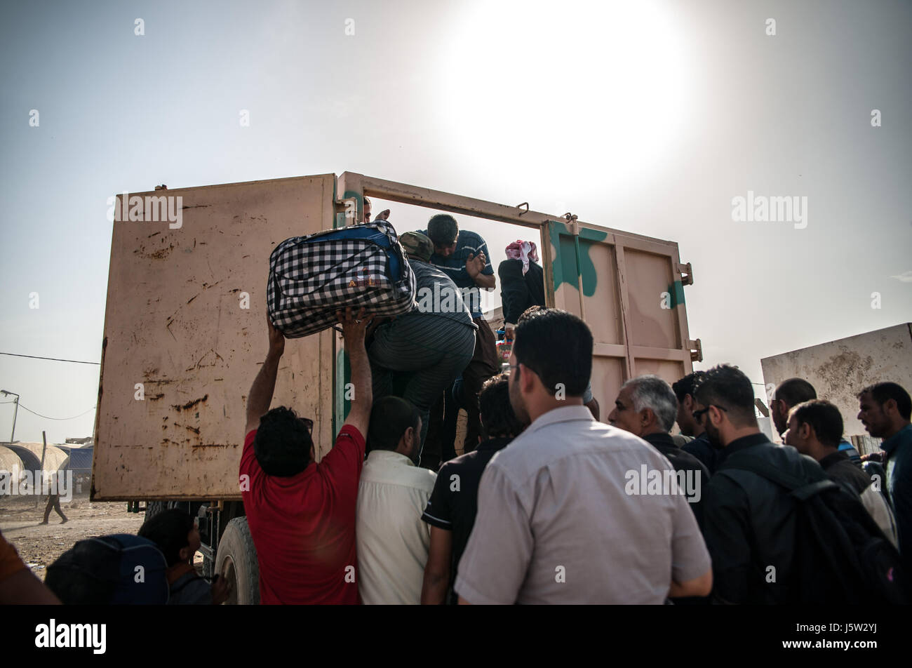 Eine Gruppe von vertriebenen Flüchtlingen Klettern auf einen LKW zu Hammam al Alil Verschiebung Camp, Irak Stockfoto