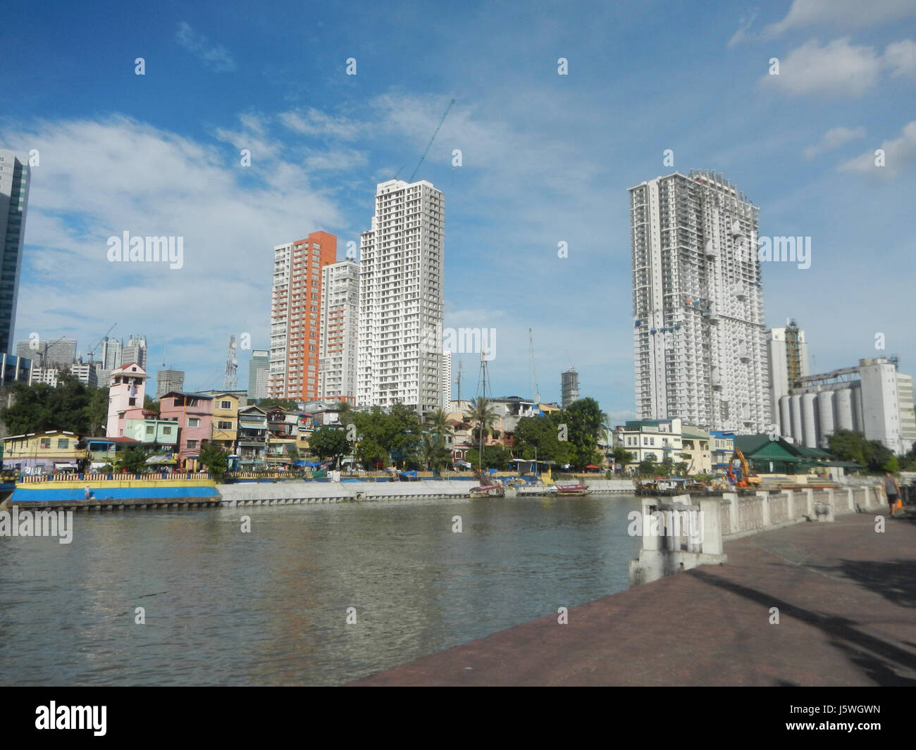 Dieses Bild oder diese Referenz zeigt den Pasig River Park Baywalk, einen malerischen Fußweg in Metro Manila, der Mandaluyong und Makati verbindet. Es bietet einen Blick auf den Pasig River und die städtische Umgebung, wobei die J.P. Rizal Street eine bedeutende Durchgangsstraße in der Gegend darstellt. Stockfoto
