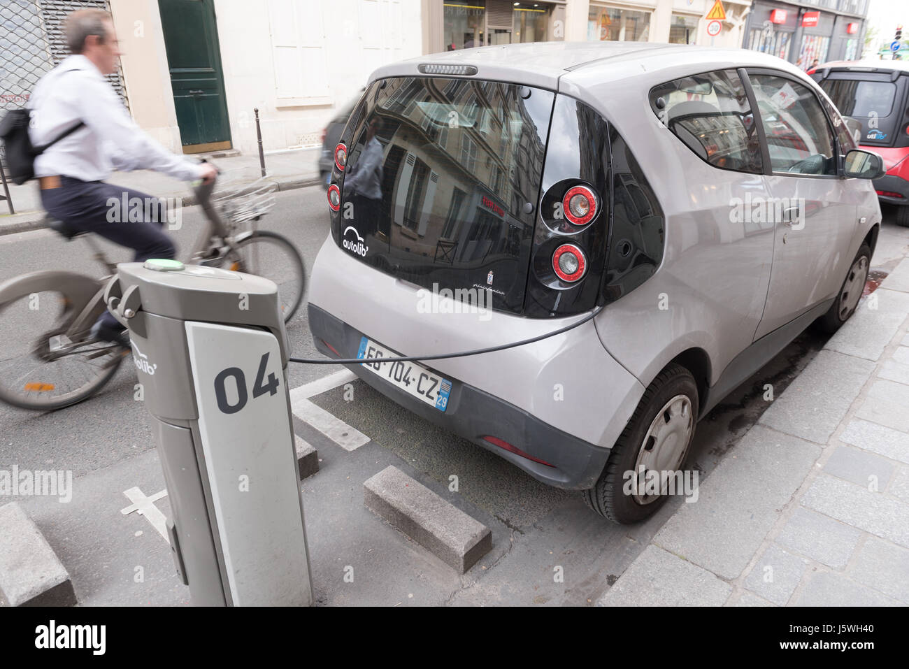Paris, Frankreich 13. Mai 2017: Autolib Auto aufladen in einer Straße von Paris mit einem verschwommenen Fahrrad Stockfoto