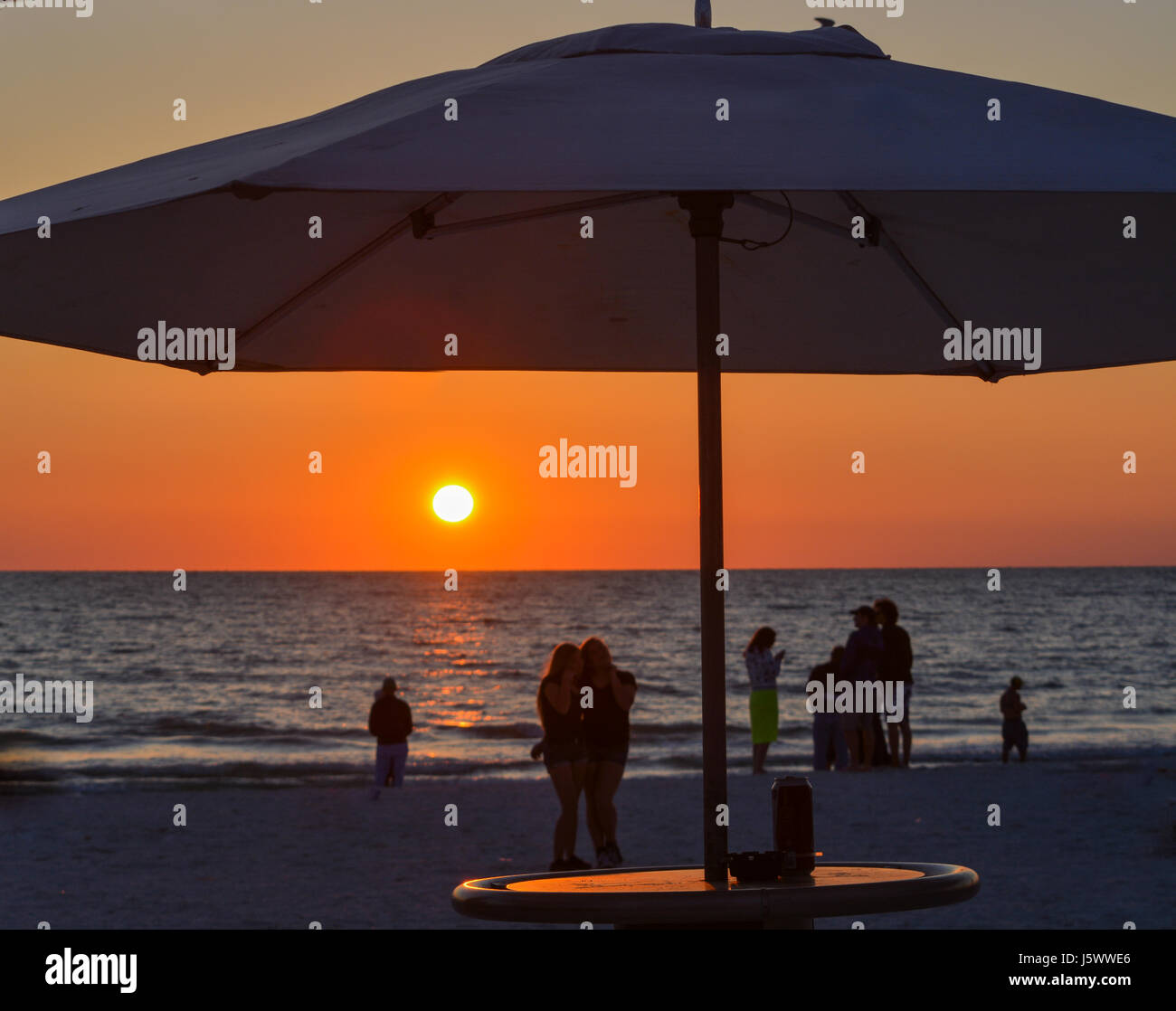 Den Sonnenuntergang mit der Silhouette eines Regenschirm und Menschen am Strand. Dies ist in Indian Rocks Beach, Golf von Mexiko, Florida Stockfoto