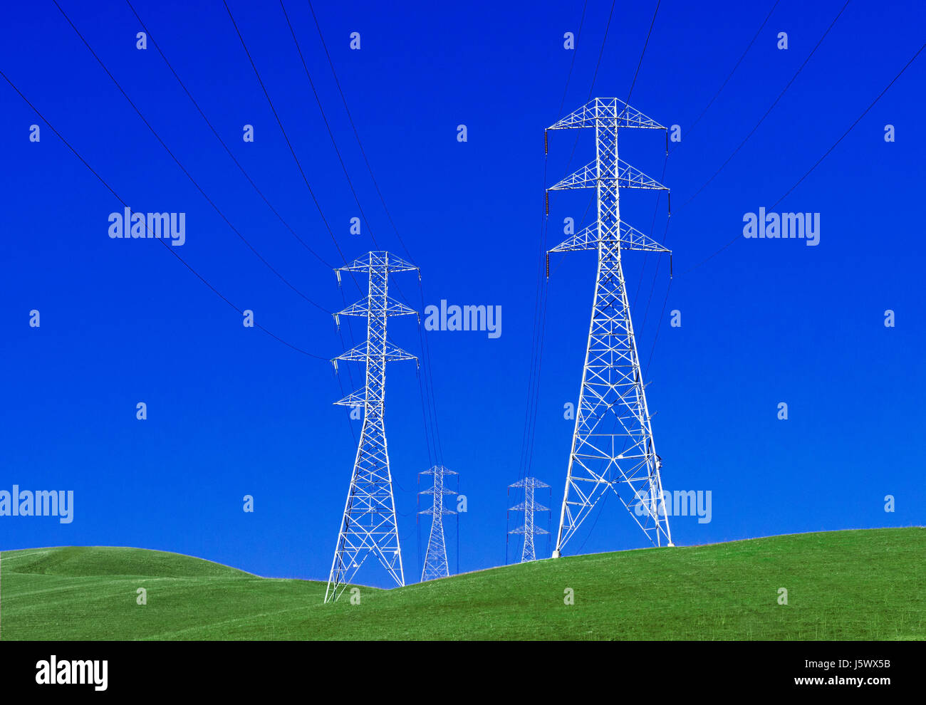 Grüne Energie Konzept von Strommasten stehen auf idealistische tiefgrünen Rasen Hügellandschaft mit klaren blauen Himmel Stockfoto