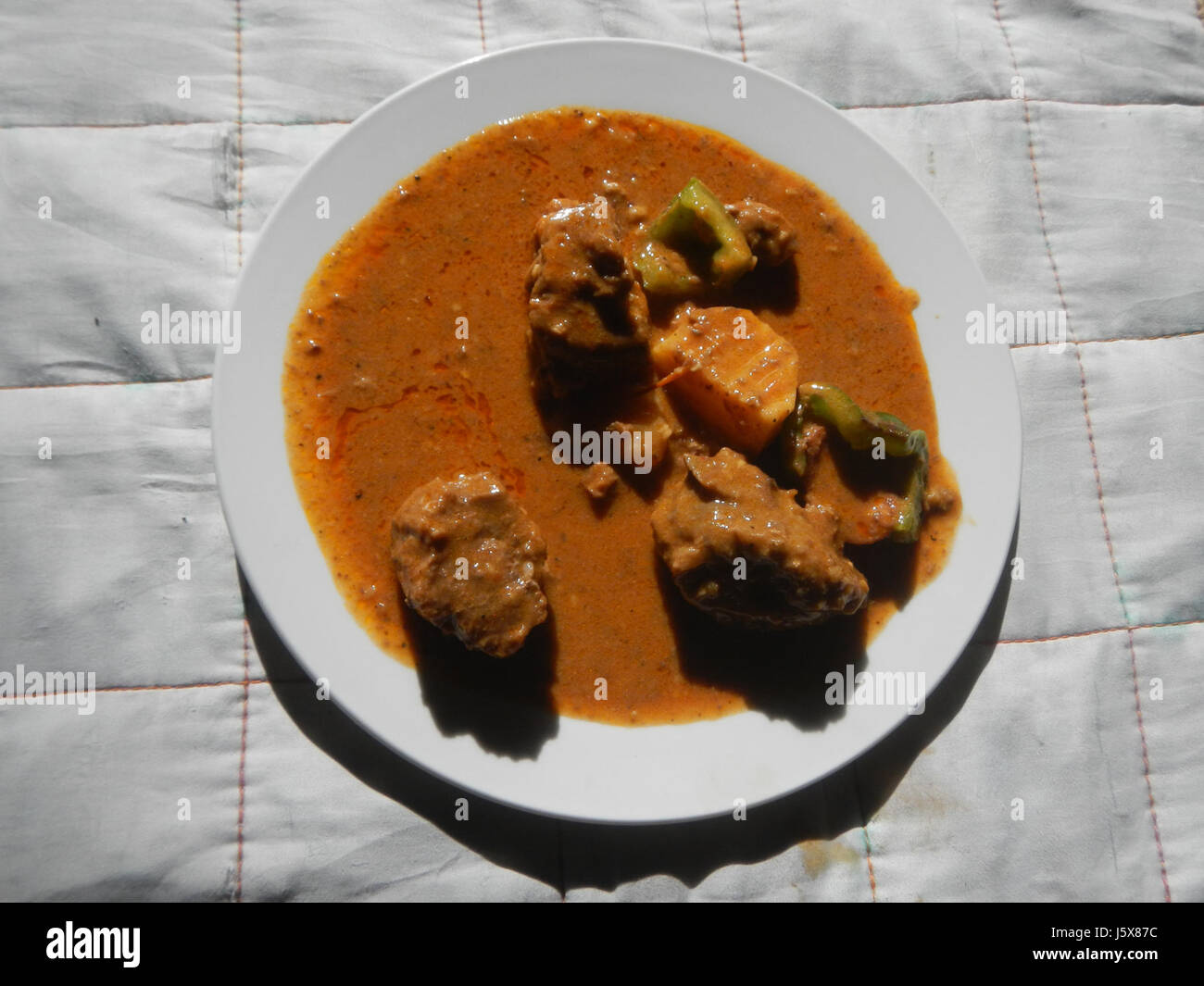 Dieses Bild bezieht sich auf ein traditionelles Gericht aus Bulacan auf den Philippinen: Caldereta. Das Gericht besteht aus gehacktem Gemüse, gekocht mit Fleisch in einer reichhaltigen Tomatensoße. Es ist ein bekannter Teil der philippinischen Küche, die oft für festliche Anlässe zubereitet wird. Stockfoto