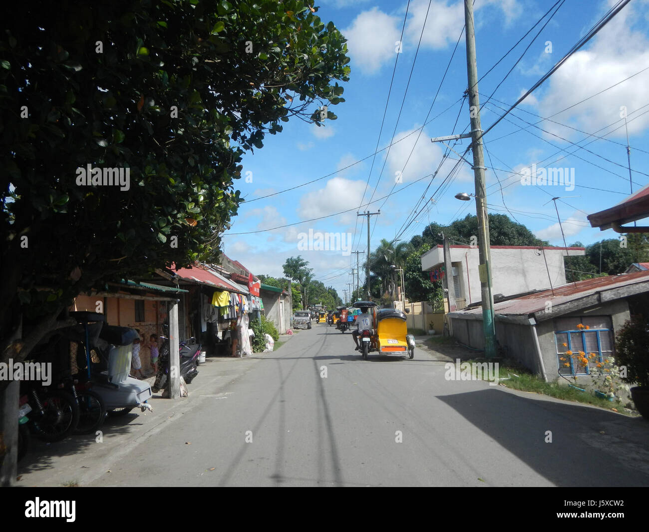 Diese Straße in Plaridel, Bulacan, Philippinen, ist Teil eines ländlichen Infrastrukturprojekts, das landwirtschaftliche Gebiete mit größeren Märkten verbindet. Sie spielt eine entscheidende Rolle bei der Verbesserung des Verkehrs und des Zugangs zu wirtschaftlichen Chancen für die lokalen Landwirte. Stockfoto