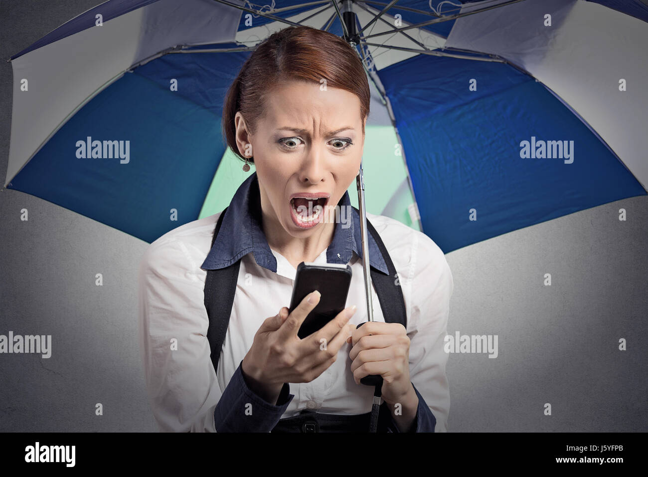 Closeup Portrait schockiert überrascht Frau corporate Manager lesen schlechte Nachrichten auf Smartphone-Dach vor Regen geschützt ist Stockfoto