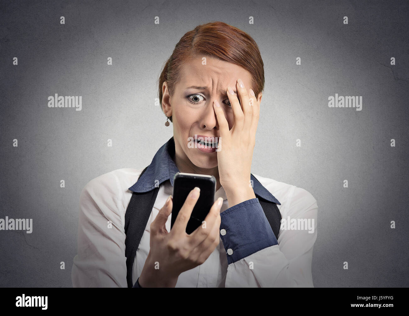 Verärgert gestresst Frau mit Handy angewidert schockiert mit der Nachricht, dass sie isolierten grauen Hintergrund erhalten. Lustig aussehende menschliches Gesicht Ausdruck emoti Stockfoto