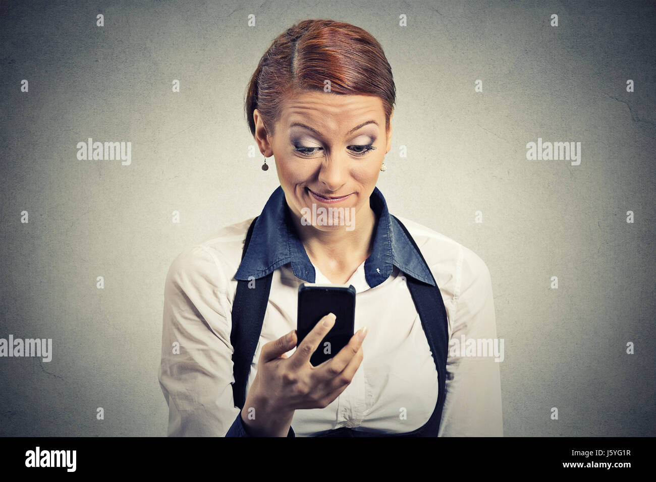 Closeup Portrait ernsthaft besorgt unzufrieden junge Geschäftsfrau lesen schlechte Nachrichten auf Smartphone hält mit mobilen isolierte graue Wand Büro Hinterg Stockfoto