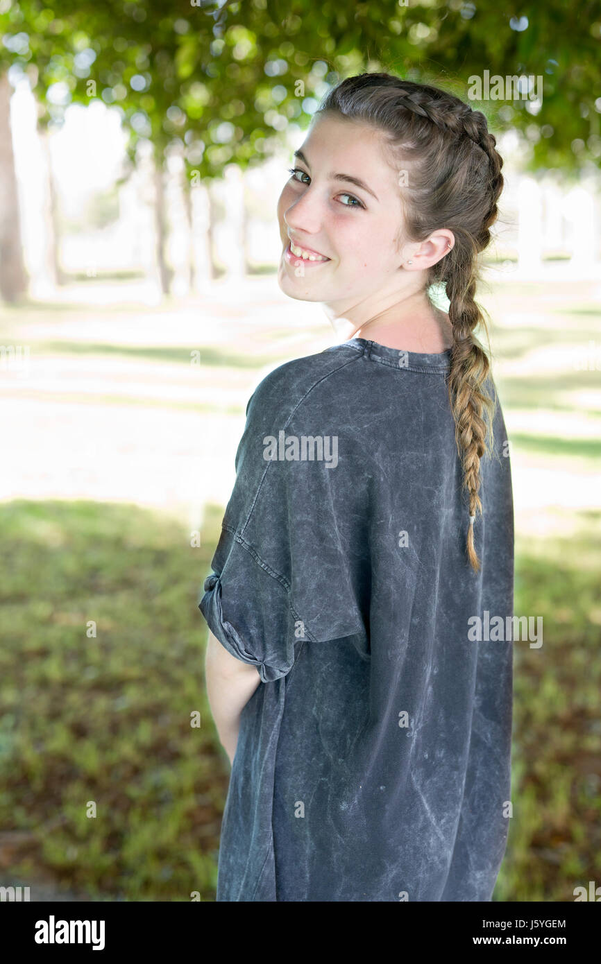 Mädchen im grauen Kleid lächelnd in Gärten der Universität Alicante, Spanien. Stockfoto