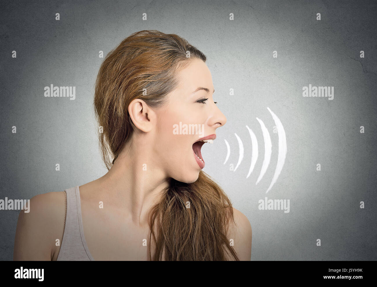 Porträt junge Frau im Gespräch mit Schallwellen aus dem Mund kommen isoliert graue Wand Background. Menschlichen Gesichtsausdrücke Stockfoto