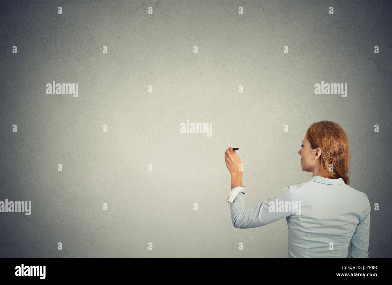 junge Geschäftsfrau erschossen hinter Schrift an der Wand Stockfoto