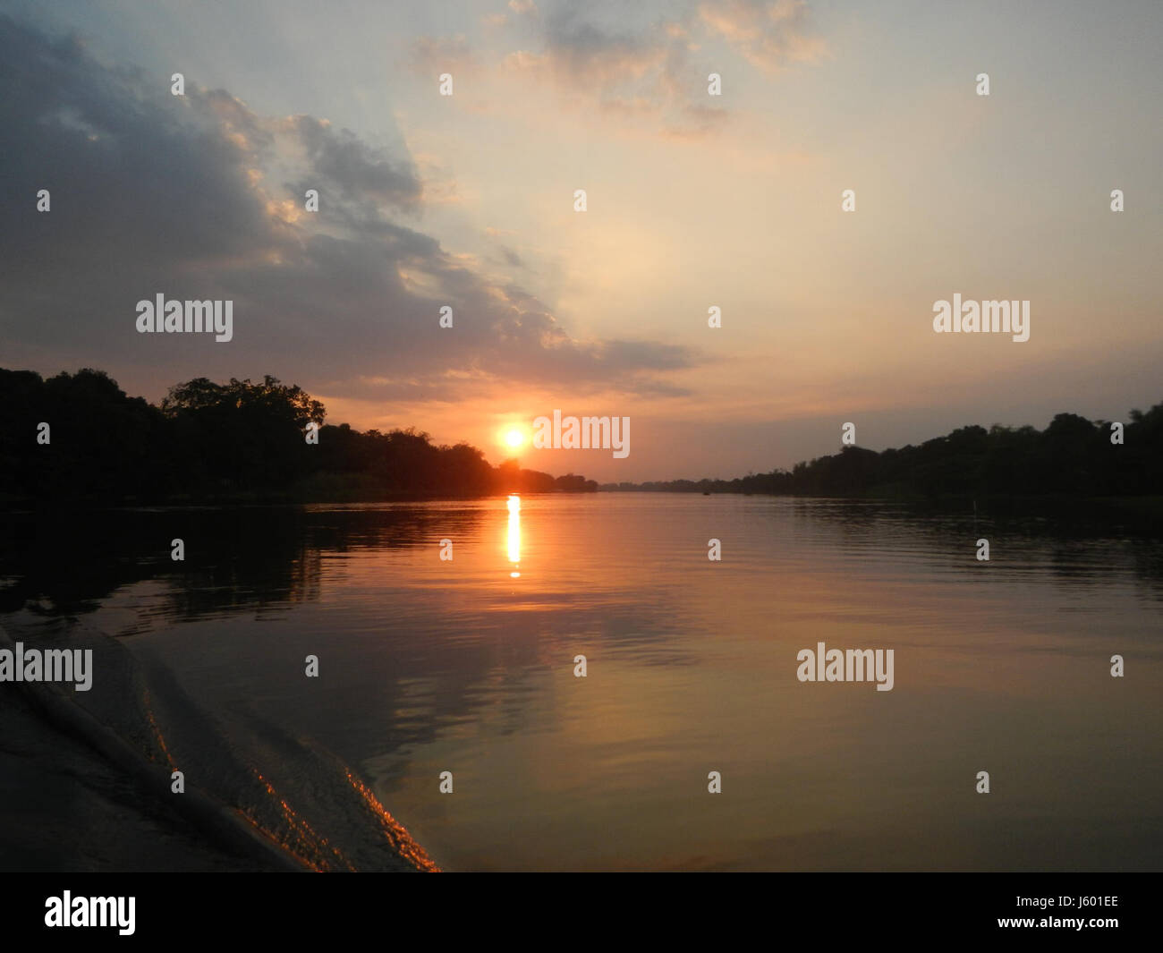 Ein ruhiger Blick auf einen Sonnenuntergang über den Flussbezirken von Calumpit, Bulacan. Das Bild fängt die natürliche Schönheit der Gegend ein, mit dem Sonnenuntergang über der Landschaft und reflektierendem Wasser. Stockfoto