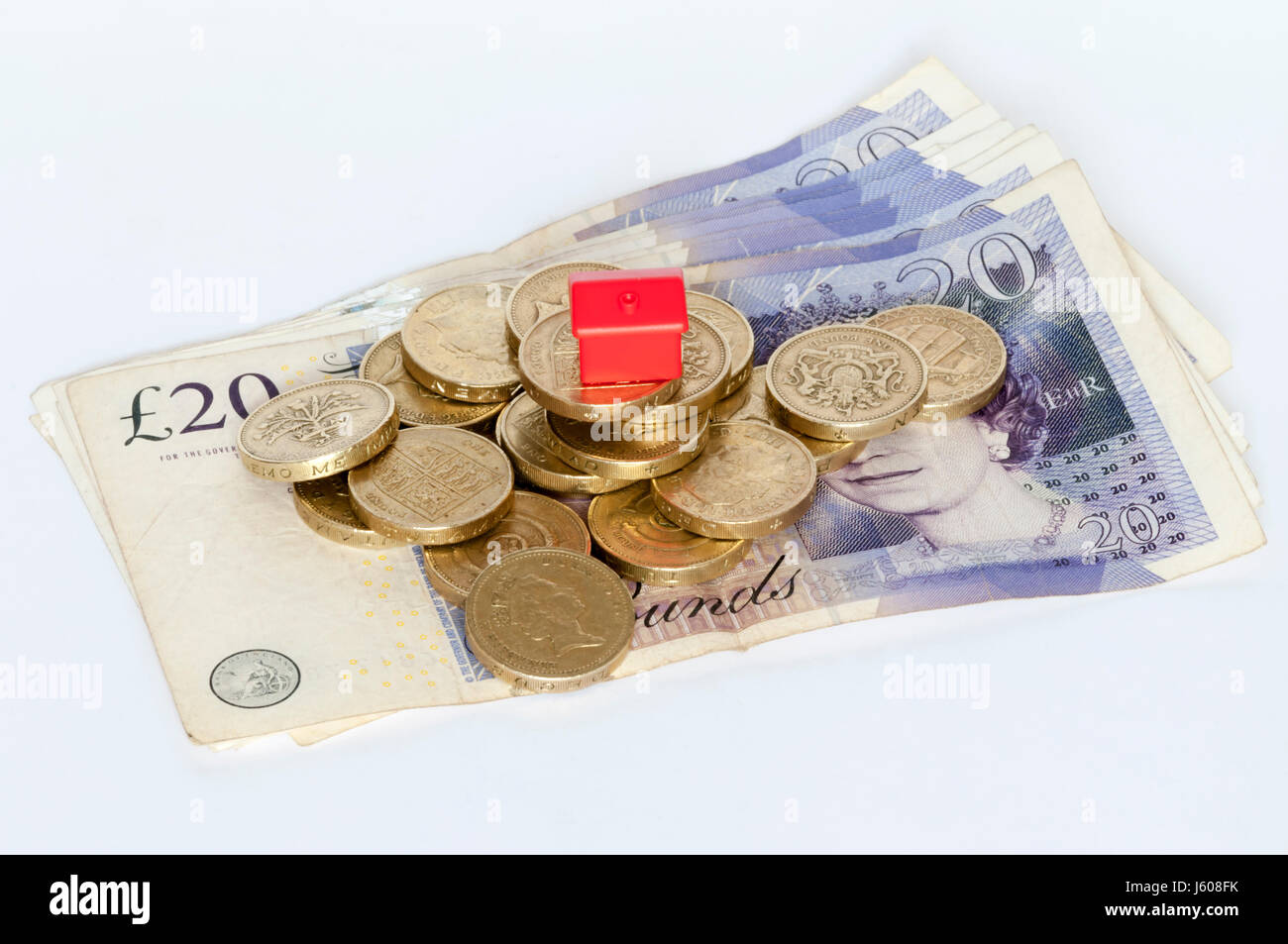Eine kleine Plastikmodell rote Haus oben auf einem Stapel von Pfund-Münzen.  Housing Finance, Immobilienfinanzierung oder Immobilien-Konzept. Stockfoto