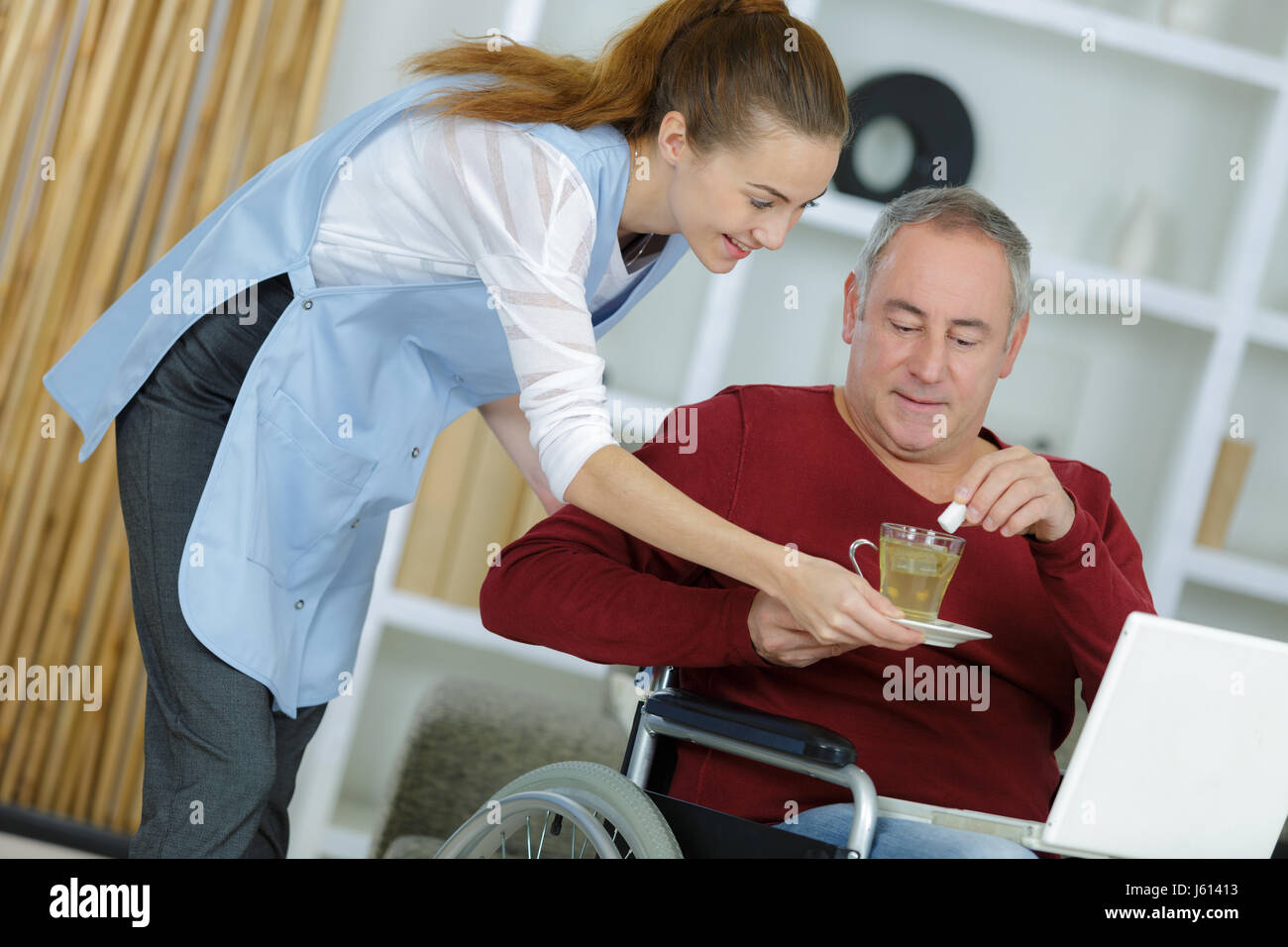 Pflegeperson geben Getränk Mann im Rollstuhl Stockfoto