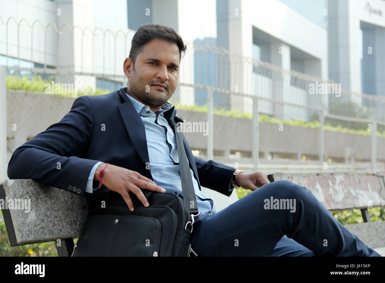 Junge indische Unternehmen Mann im Anzug auf der Bank sitzen und Lächeln Stockfoto