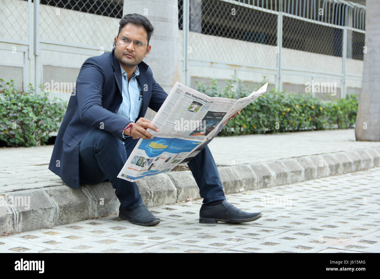 Junge indische Unternehmen Mann im Anzug mit Bluetooth-Lautsprecher, eine Zeitung lesen Stockfoto