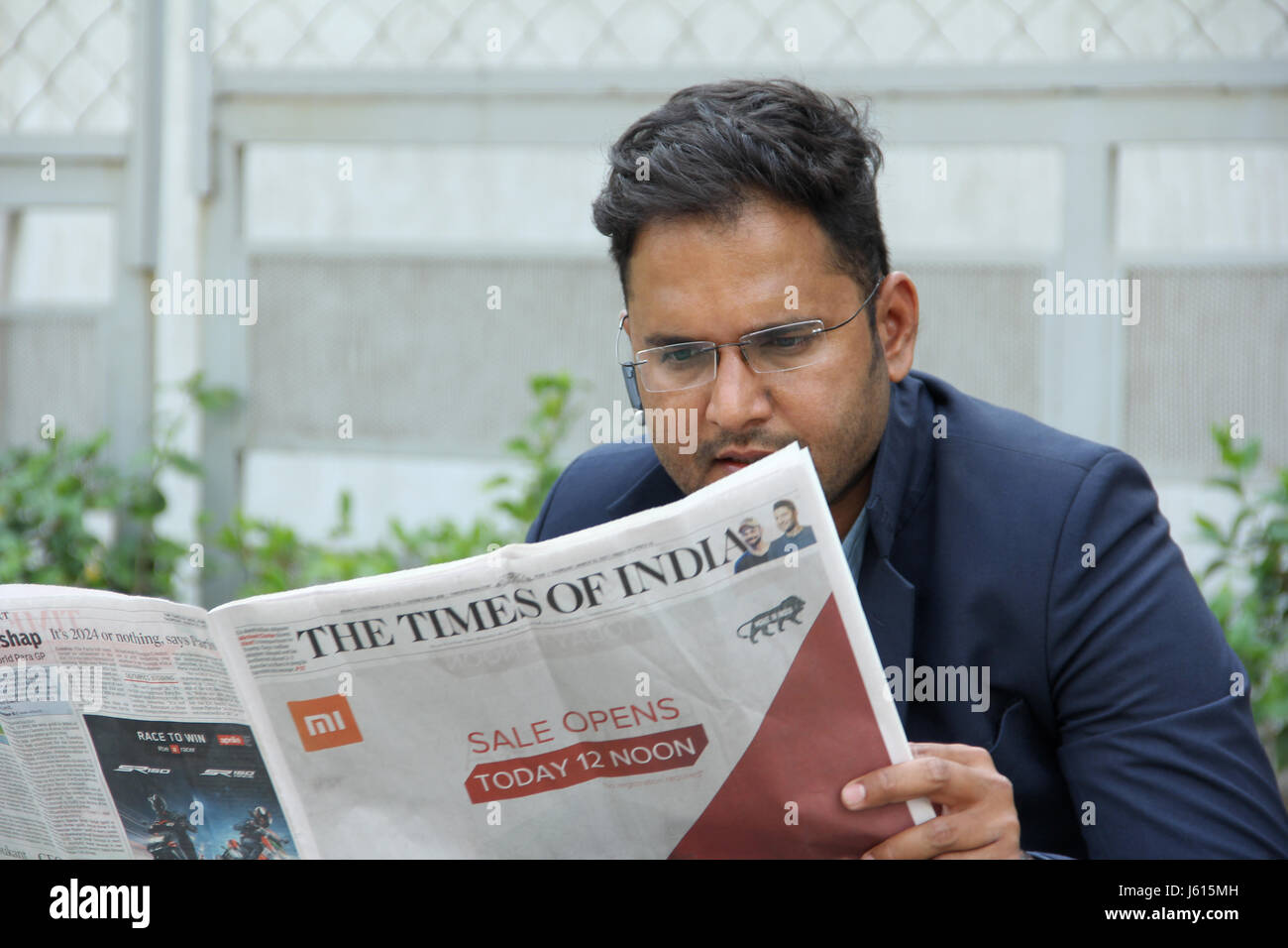 Junge indische Unternehmen Mann im Anzug mit Bluetooth-Lautsprecher, eine Zeitung lesen Stockfoto