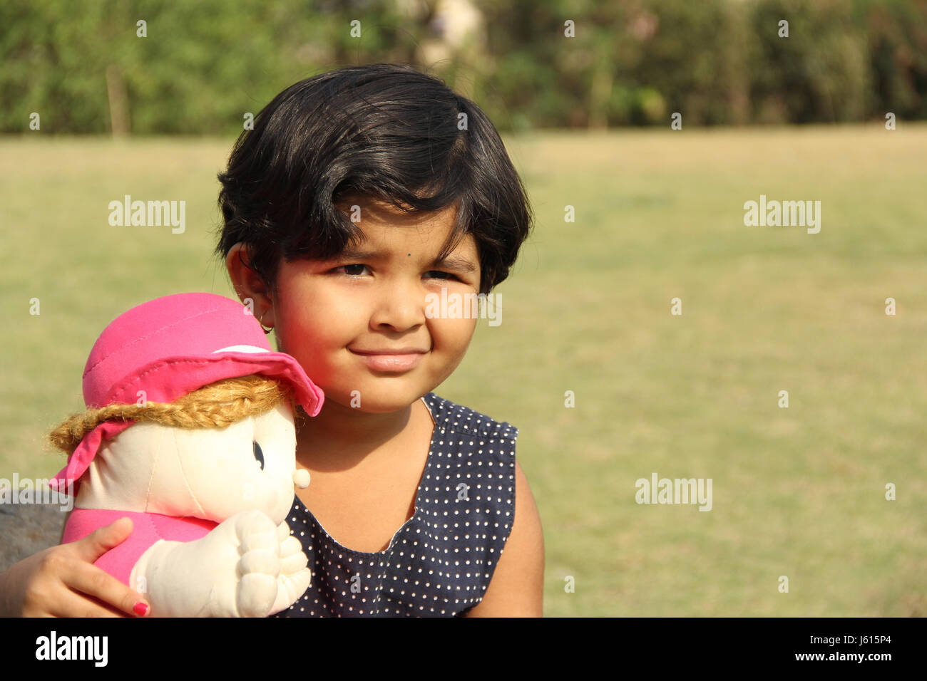 Kleine Inderin mit seiner Puppe im Garten Stockfoto