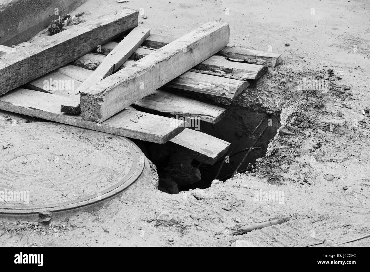 Schwarz / weiß Foto Loch im Boden mit Platten neben der Luke auf dem  Parkplatz nahe dem Speicher Stockfotografie - Alamy