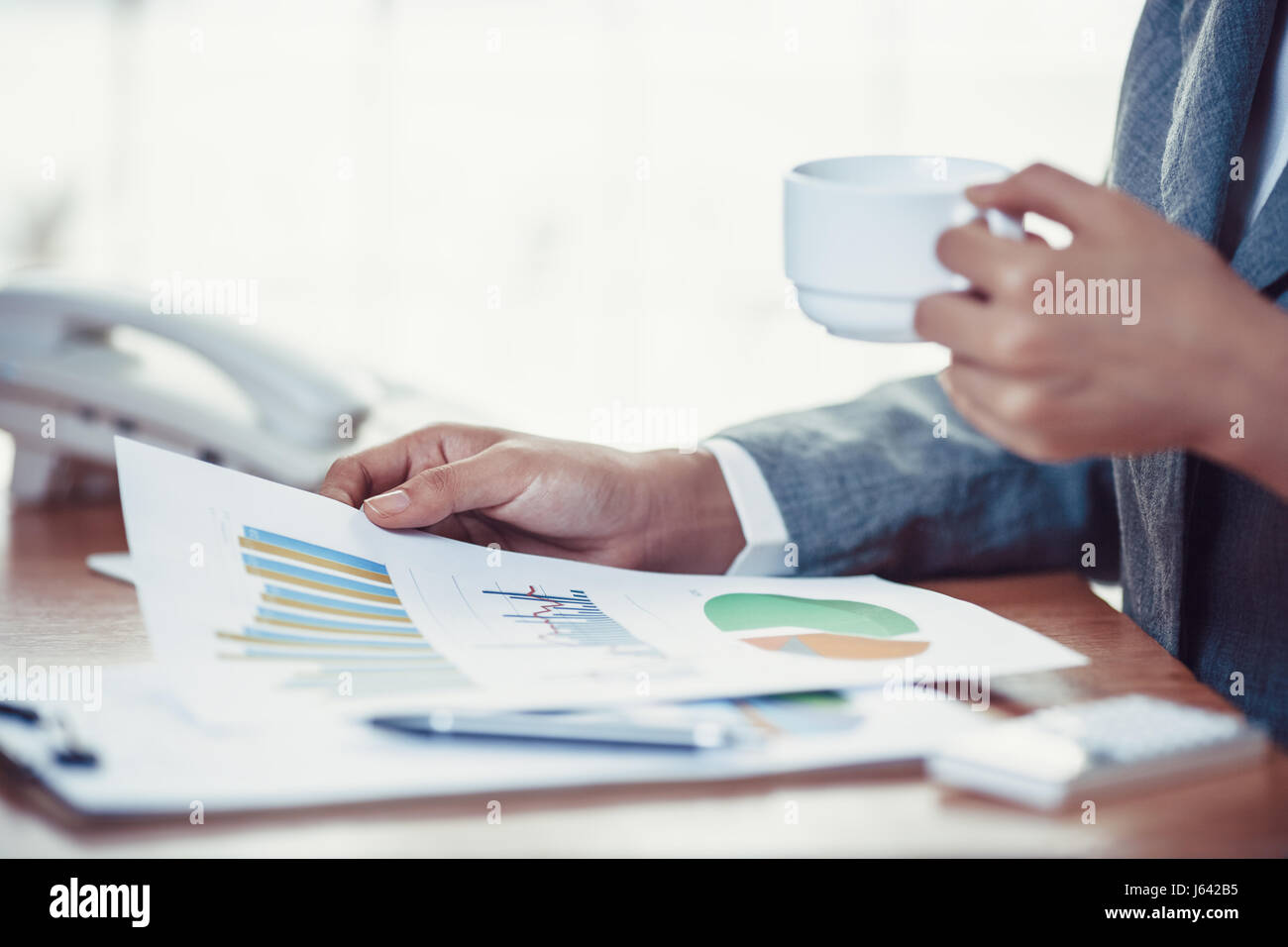 Geschäftsperson lesen finanzielle Graphen und trinken Kaffee Stockfoto