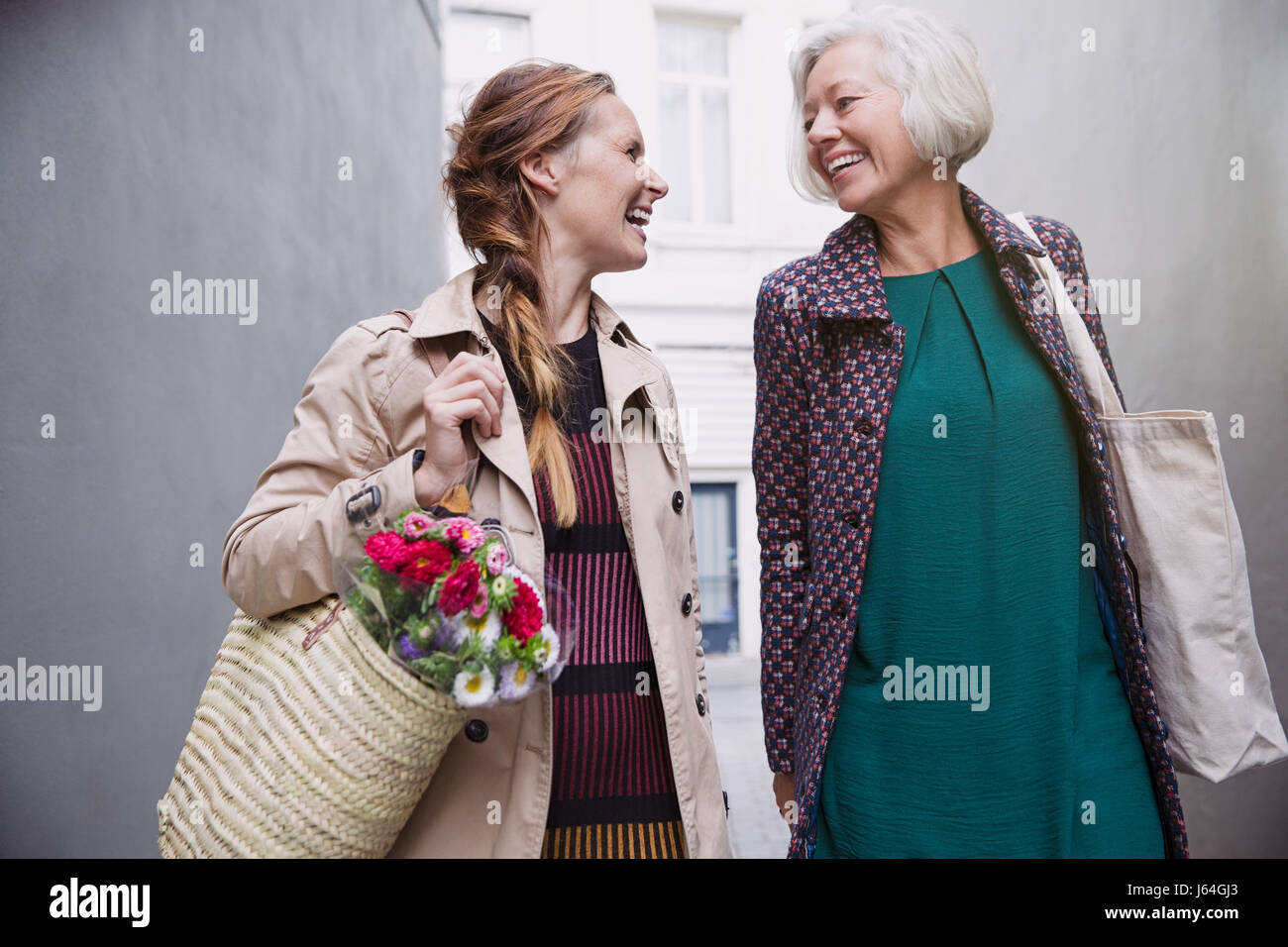 Lächelnde Mutter und Tochter mit Einkaufstüten in Gasse Stockfoto
