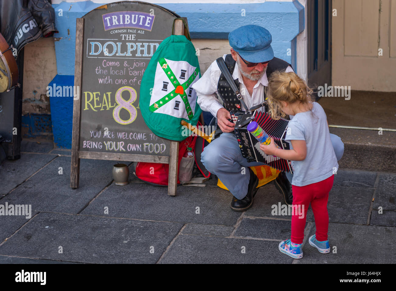 Ein junges Kind schaut neugierig ein Morris Mann Akkordeon während einer Aufführung außerhalb The Dolphin Gastwirtschaft in Plymouth. Stockfoto