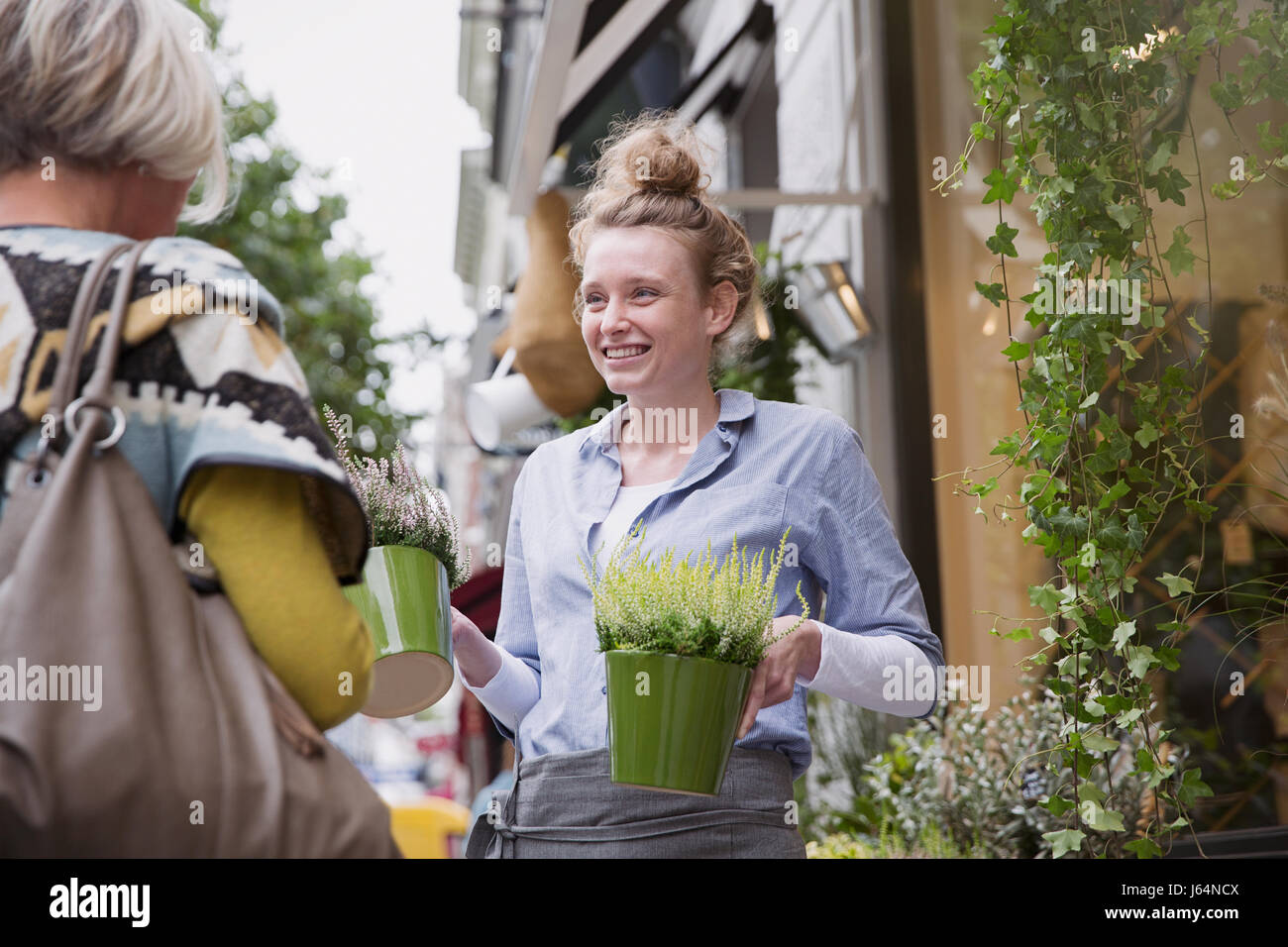 Floristen zeigen Pflanzen an weibliche Käufer im Schaufenster Stockfoto