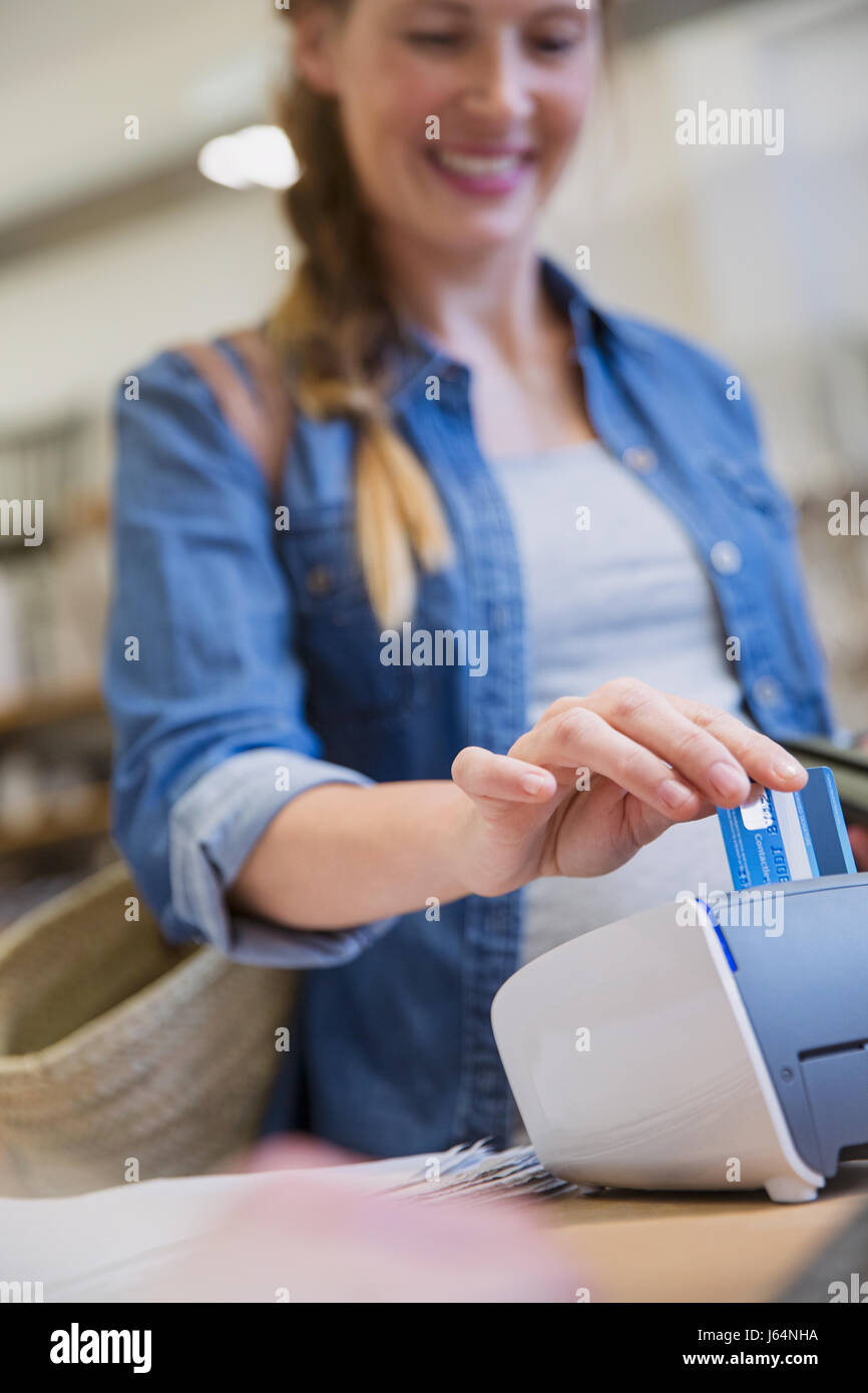 Weibliche Shopper mit Credit Card Reader im shop Stockfoto