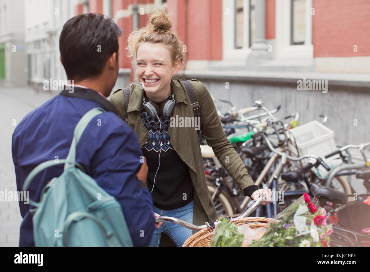 Junger Mann und Frau mit Fahrrad auf Stadtstraße lachen Stockfoto