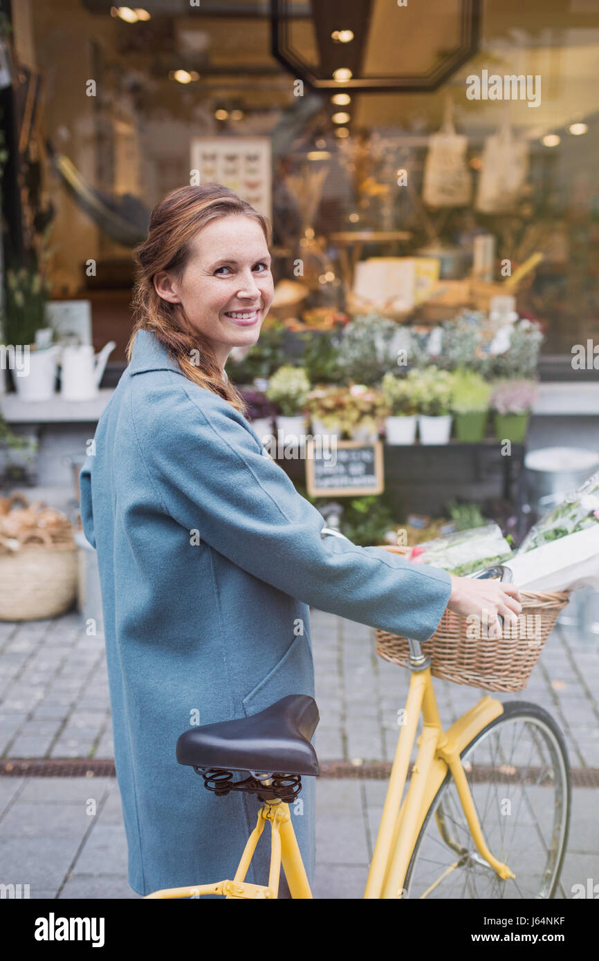 Lächelnde Frau Porträt zu Fuß Fahrrad in der städtischen Schaufenster Stockfoto