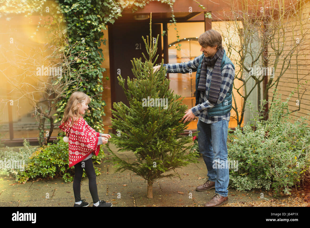 Vater und Tochter mit Weihnachtsbaum vor Haus Stockfoto