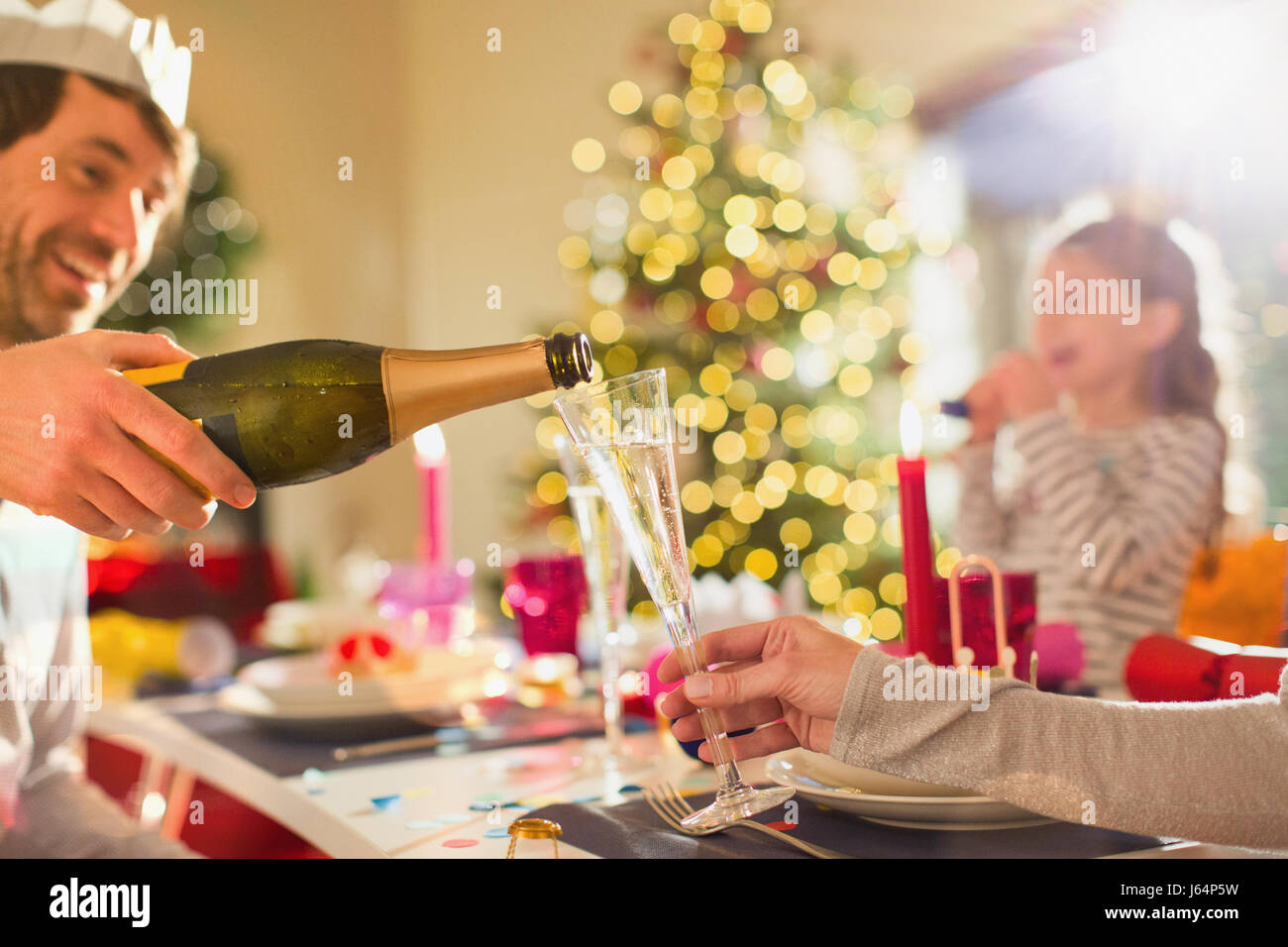 Ehemann Gießen Champagner für Frau an Weihnachten Festtafel Stockfoto