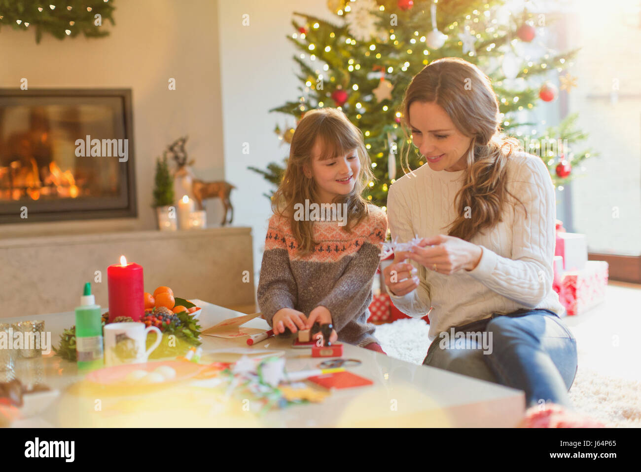 Mutter und Tochter machen Weihnachtsschmuck Schneeflocke im Wohnzimmer Stockfoto