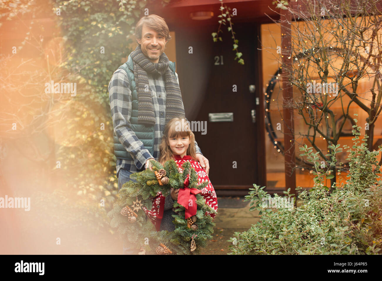 Porträt, Lächeln, Vater und Tochter hält Weihnachtskranz vor Haus Stockfoto