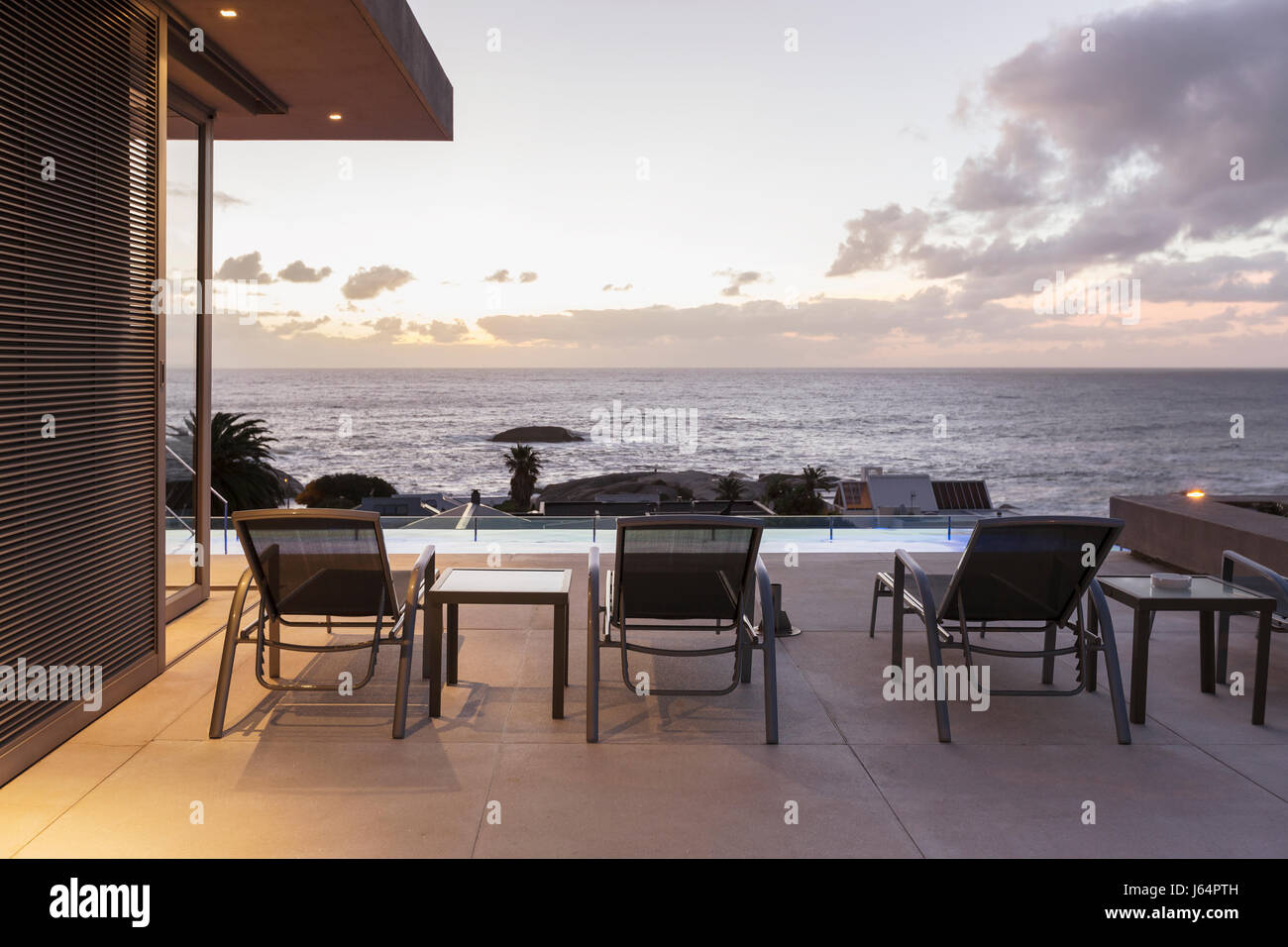 Lounge-Sessel auf Luxus-Terrasse mit Blick auf den Sonnenuntergang Ozean Stockfoto