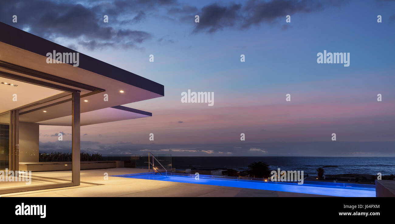 Ruhigen Dämmerung Himmel über beleuchtete home Schaufenster außen Terrasse mit Lap-pool Stockfoto