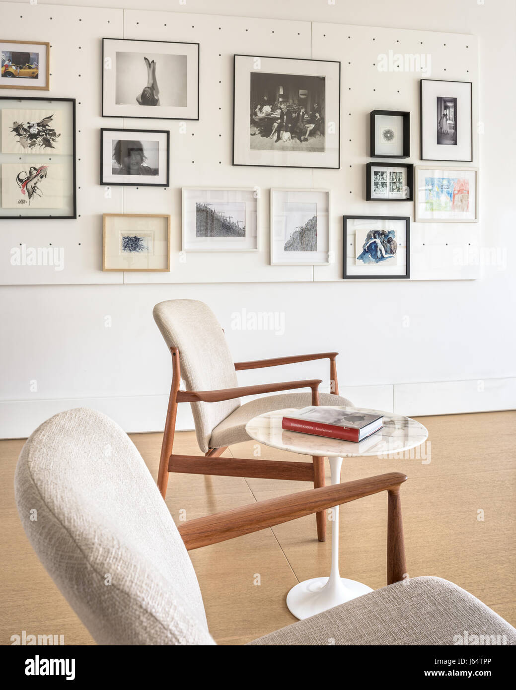 Paar Mitte des Jahrhunderts Stühle und Tulip Beistelltisch von Eero Saarinen in hellen Schlafzimmer, dekoriert mit einem Sortiment von Kunst und Fotografie. Stockfoto