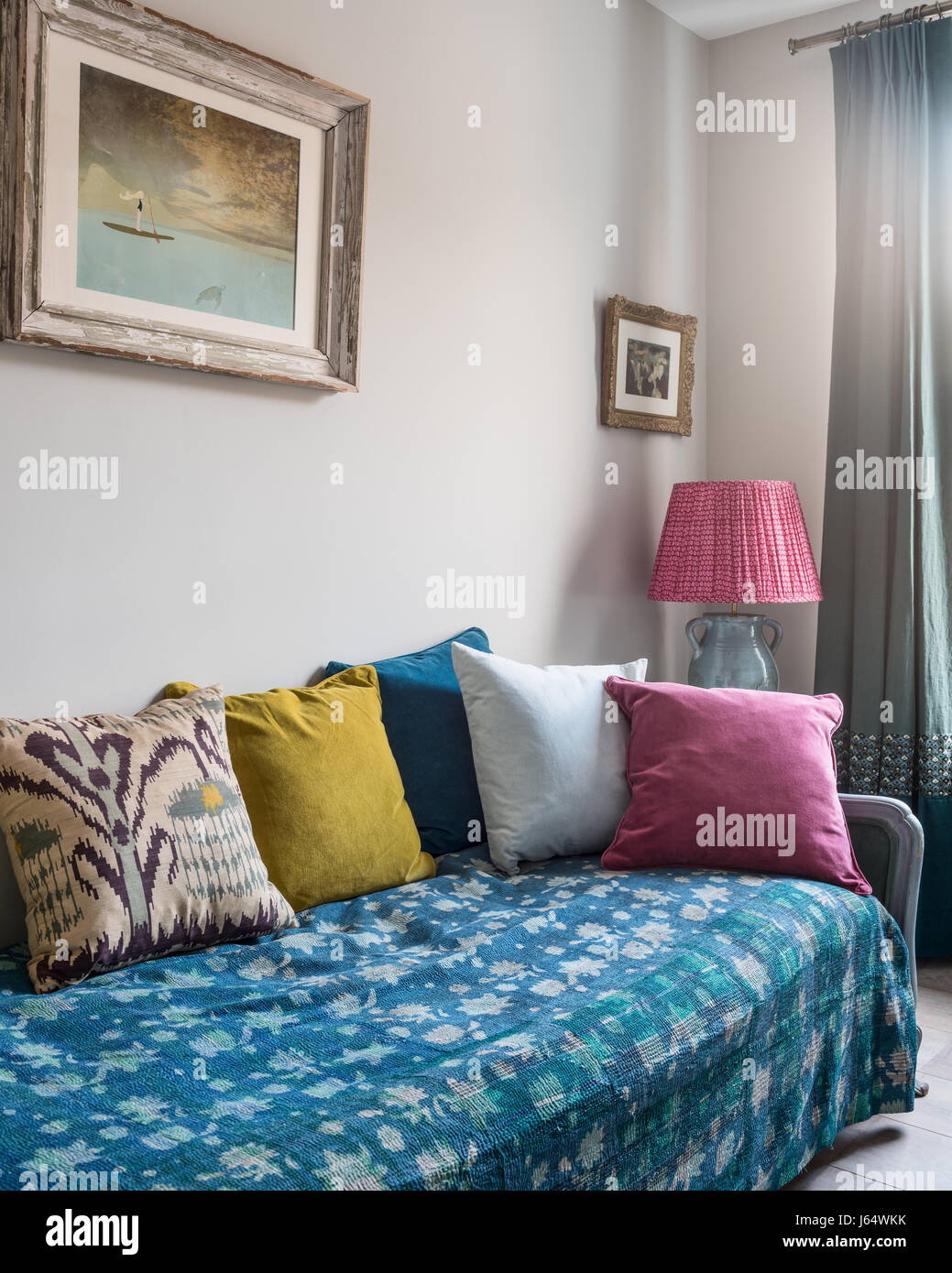 Gesteppte Kantha werfen auf Liege mit einem Sortiment von bunten samt und Ikat Kissen Stockfoto